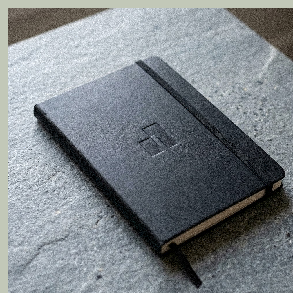 Numbers brand symbol embossed on a black notebook resting on stone