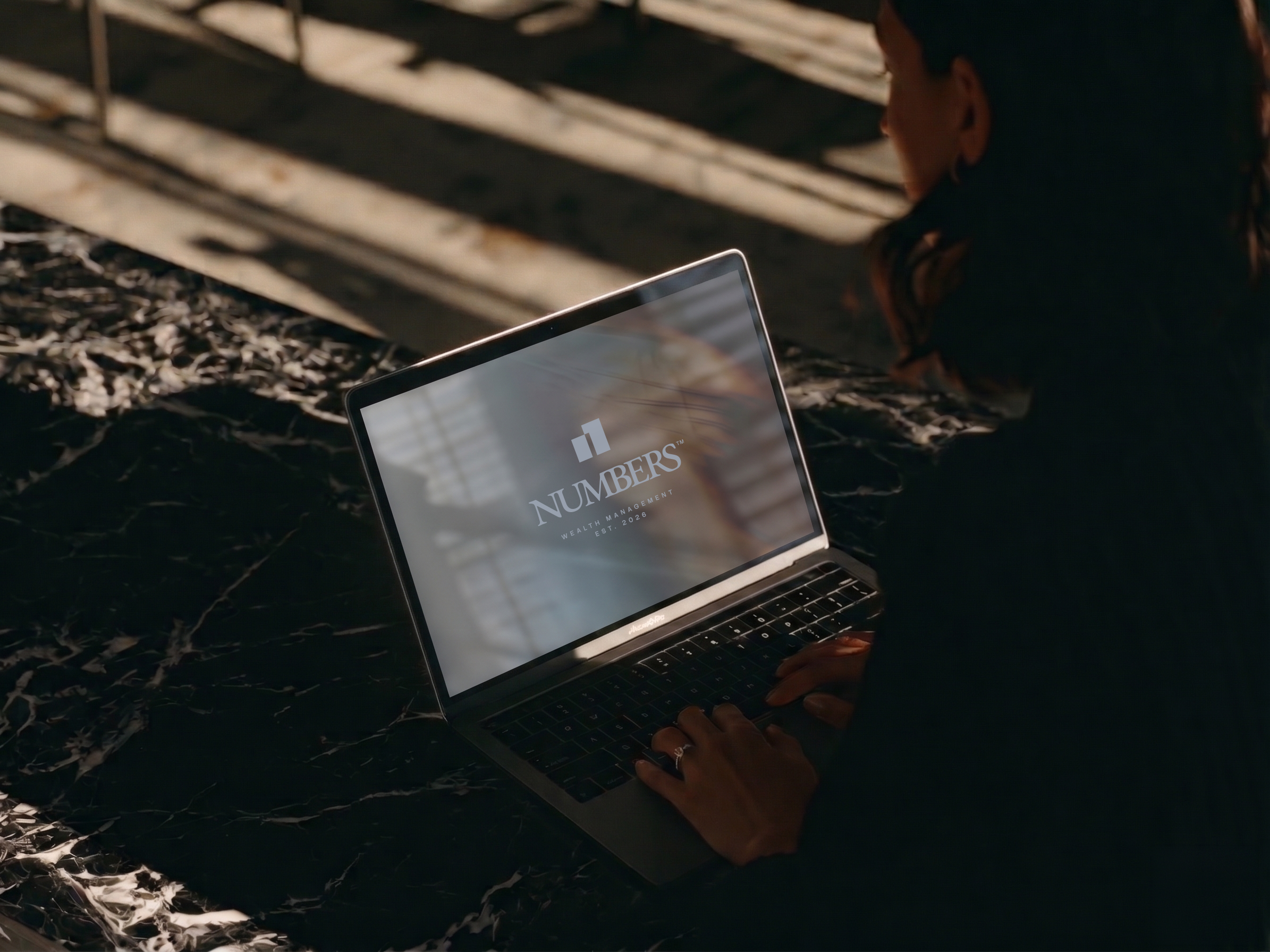 Numbers website on a laptop screen, open on a marble table in low light